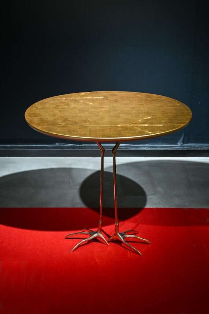 A bird-legged table stands on a red carpet.